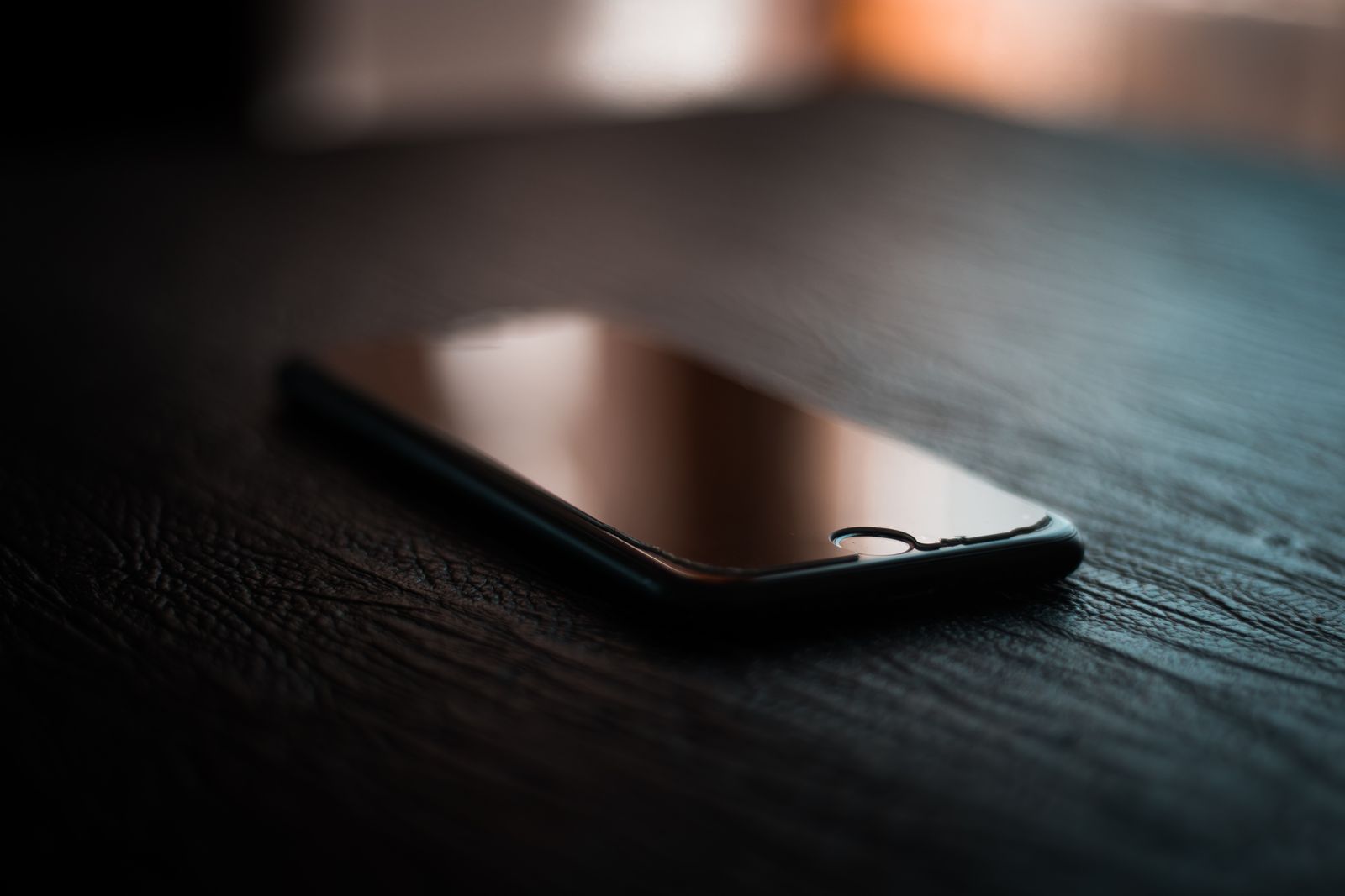 Loş masa üzerinde kapalı ekranlı telefon; iletişim için temsili görsel